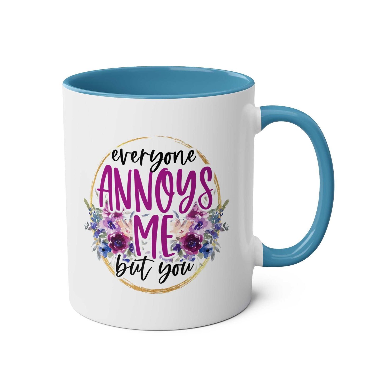 Everyone Annoys Me But You coffee mug with floral design and blue handle.