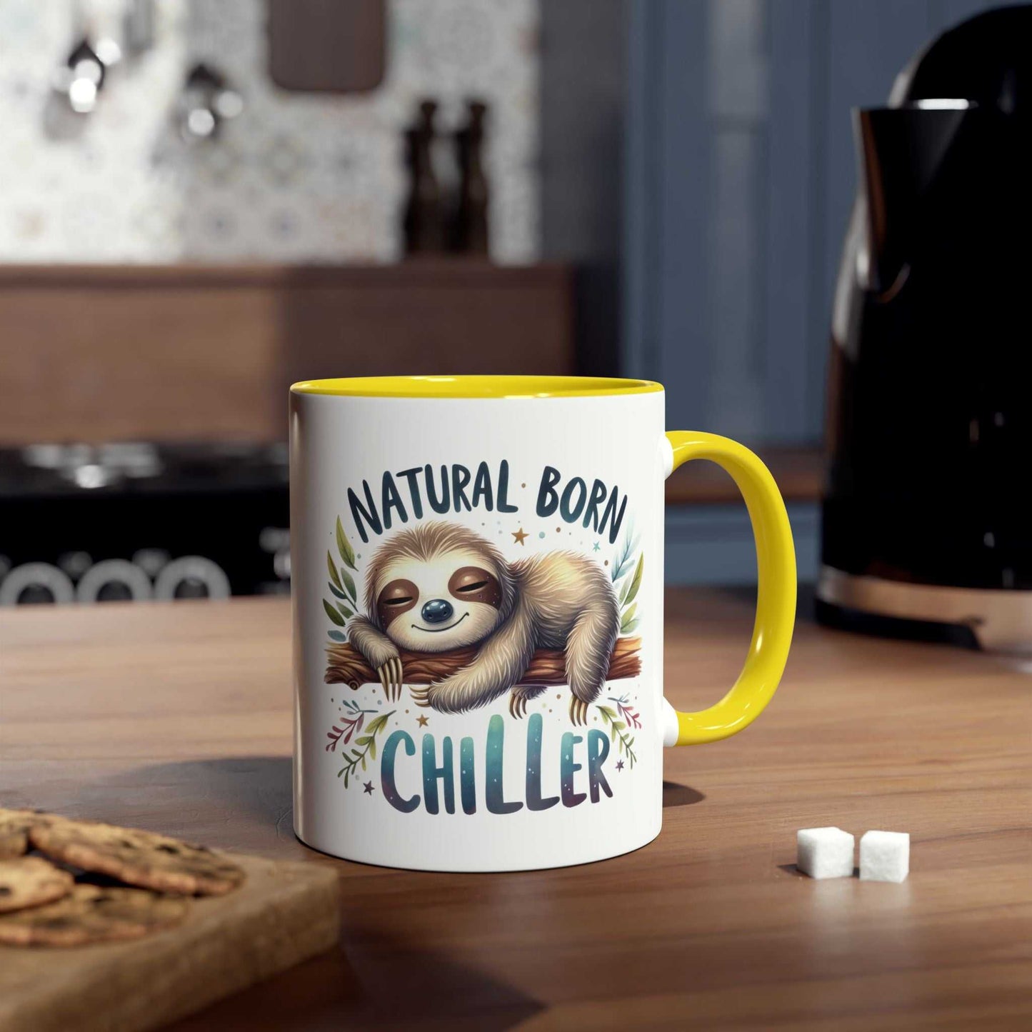 Cute sloth coffee mug with "Natural Born Chiller" design on a kitchen countertop.