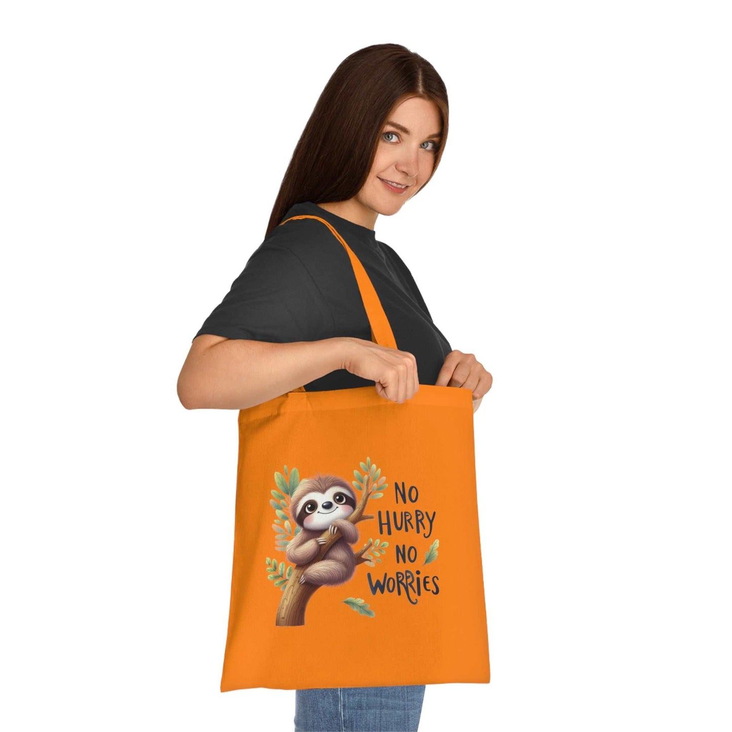 Cotton tote bag with cute sloth design, held by a person, in vibrant orange color.