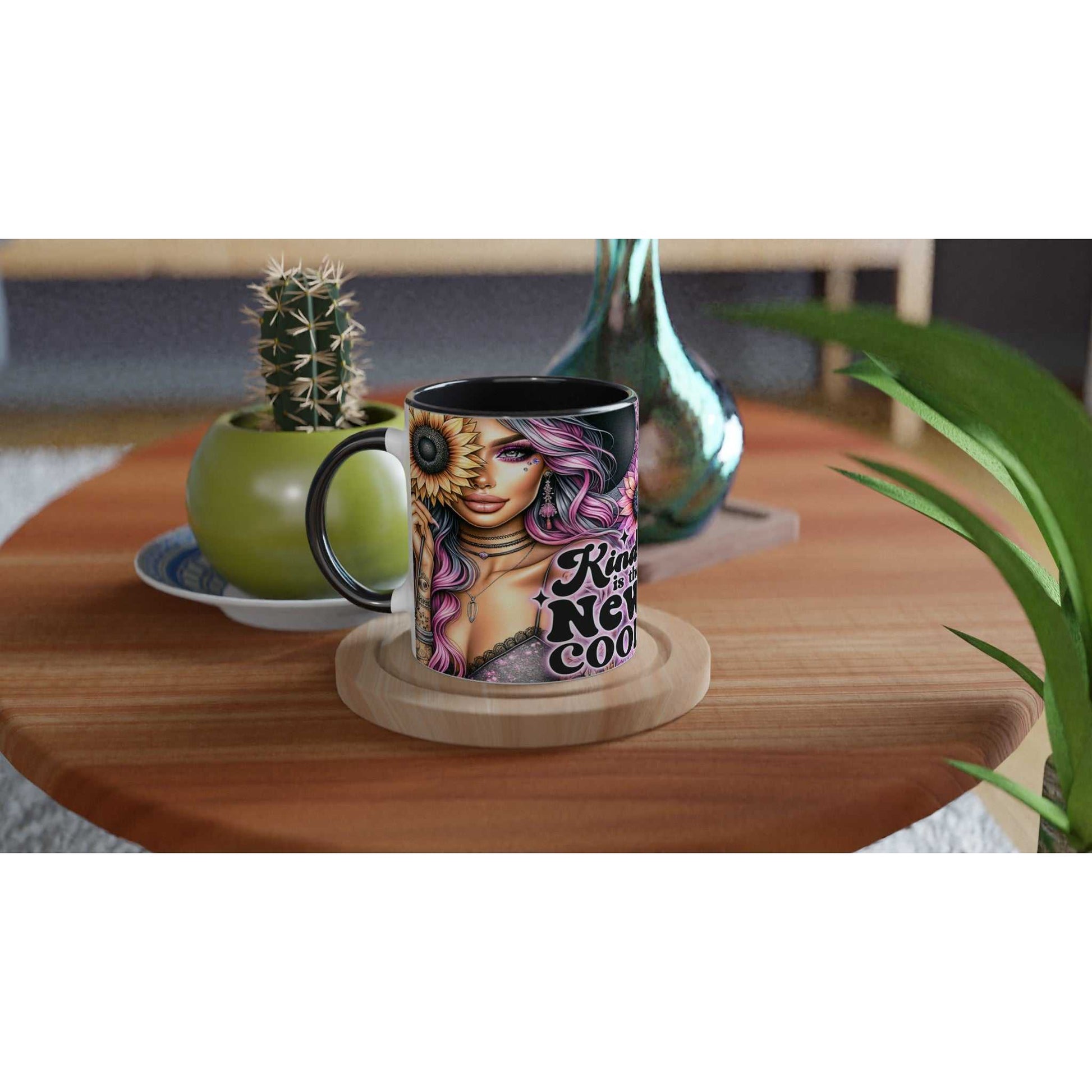 Kind Is The New Cool motivational coffee mug with vibrant design on a wooden table, surrounded by plants.