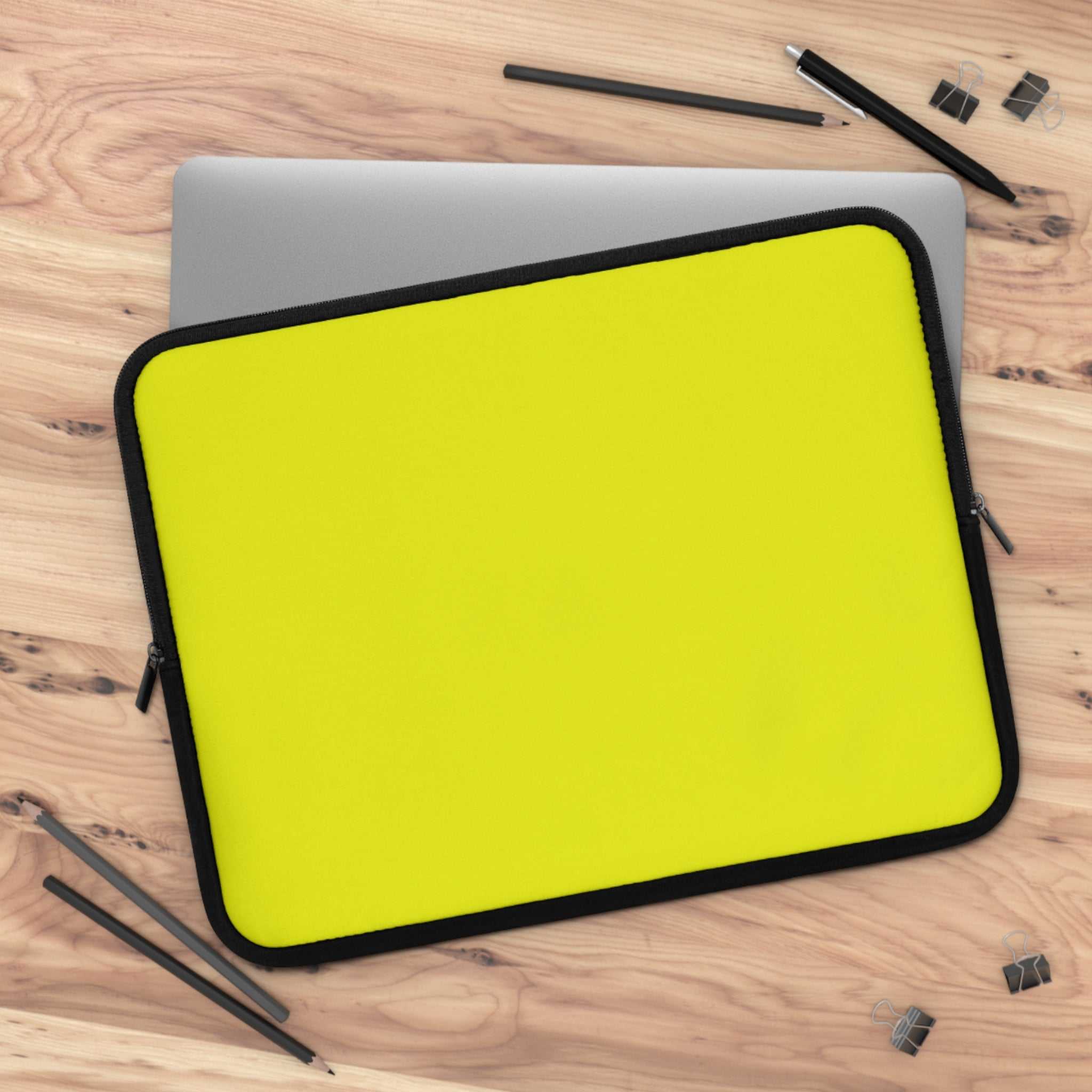 Bright yellow neoprene laptop sleeve with black trim, soft foam lining, and dual zipper closure on wooden desk