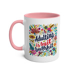 Colorful "Adulting Is Bullshit" coffee mug with floral design and pink handle.