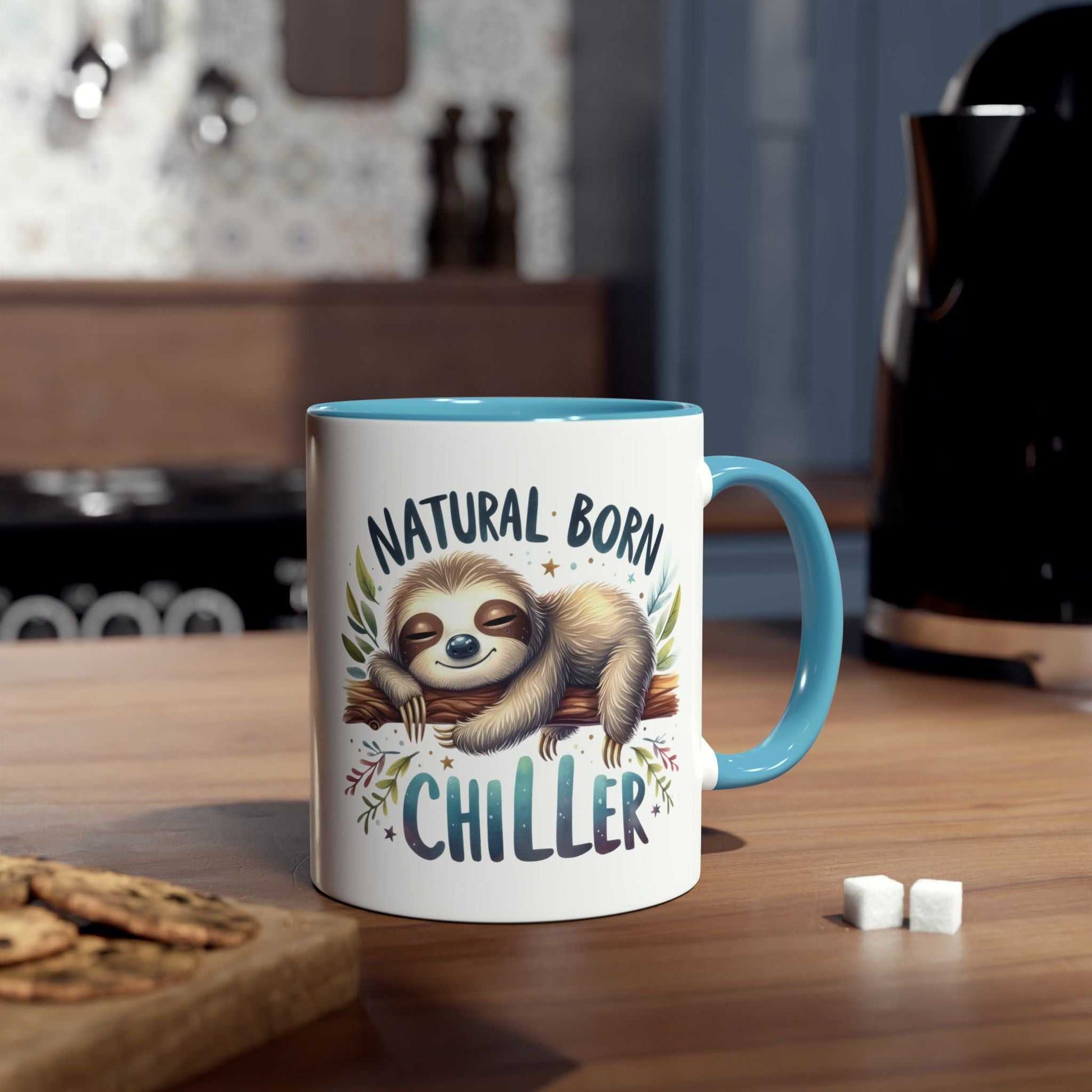 Cute sloth coffee mug with "Natural Born Chiller" design on a kitchen counter.