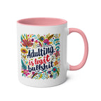 Colorful "Adulting Is Bullshit" coffee mug with floral design and pink handle.