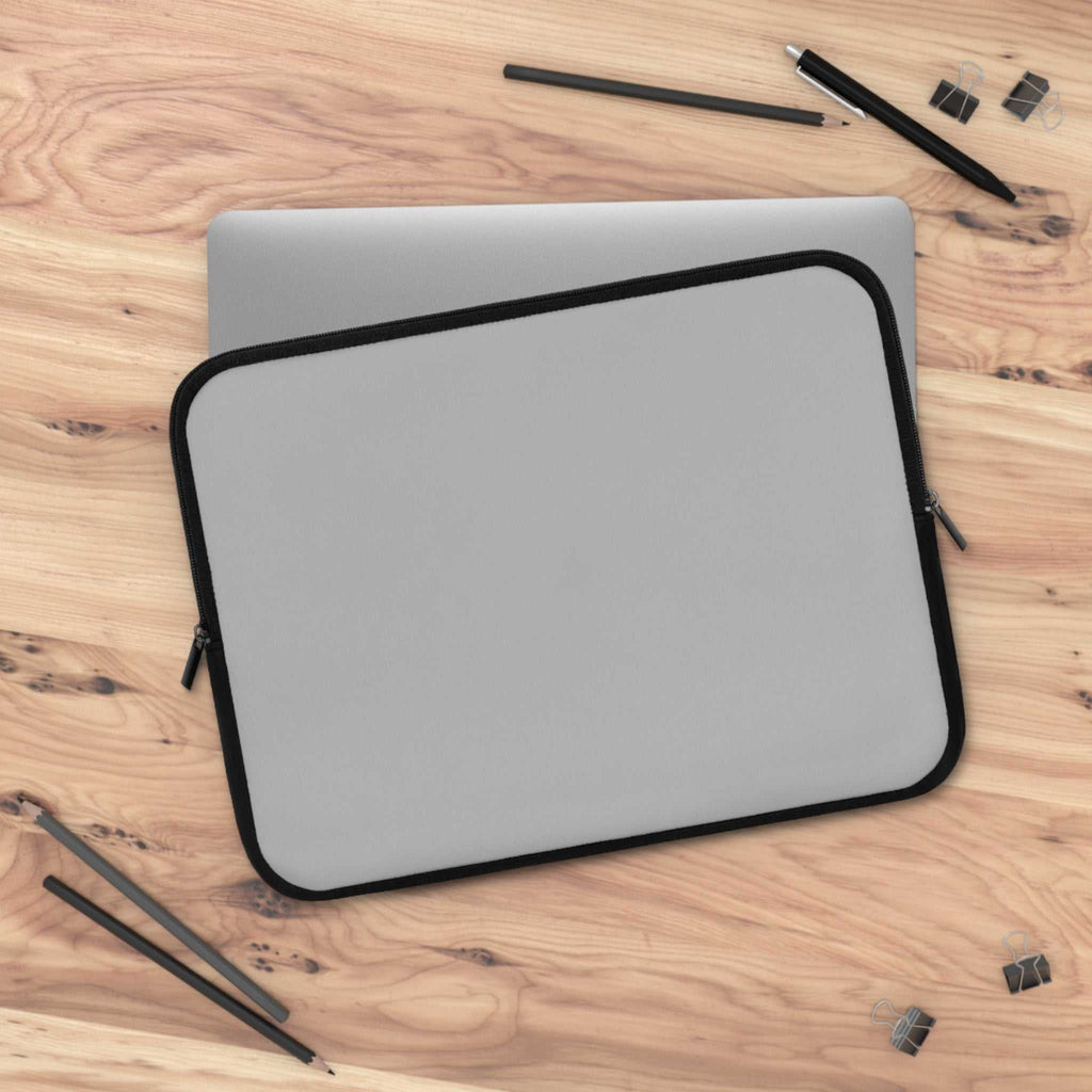 silver laptop sleeve with black trim on wooden desk with office supplies protective neoprene case
