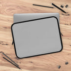 silver laptop sleeve with black trim on wooden desk with office supplies protective neoprene case
