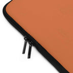 Close-up of bold orange laptop sleeve with black dual zipper and soft neoprene material
