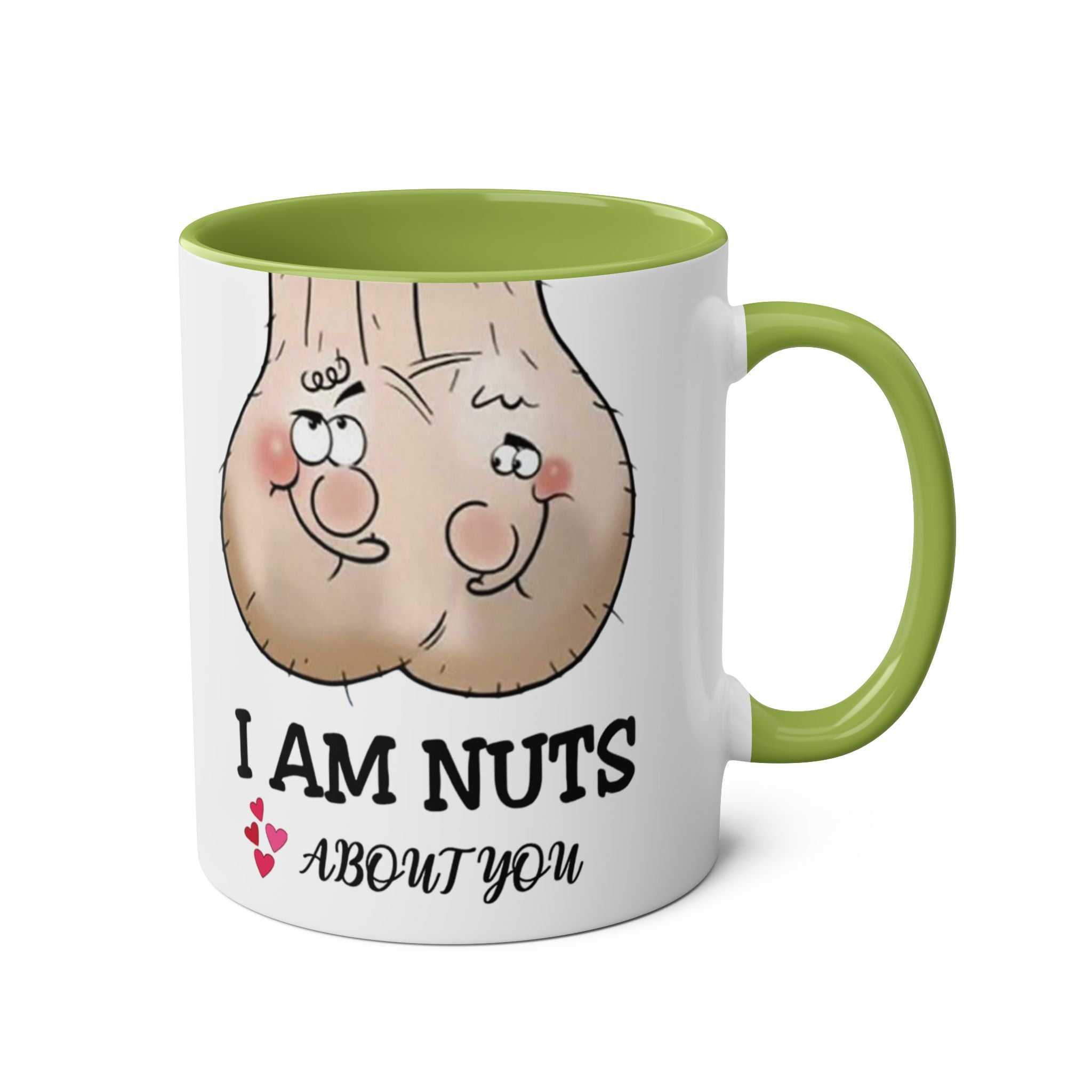 Ceramic "I Am Nuts About You" mug with green handle and interior, featuring playful nut characters and cheeky text design.