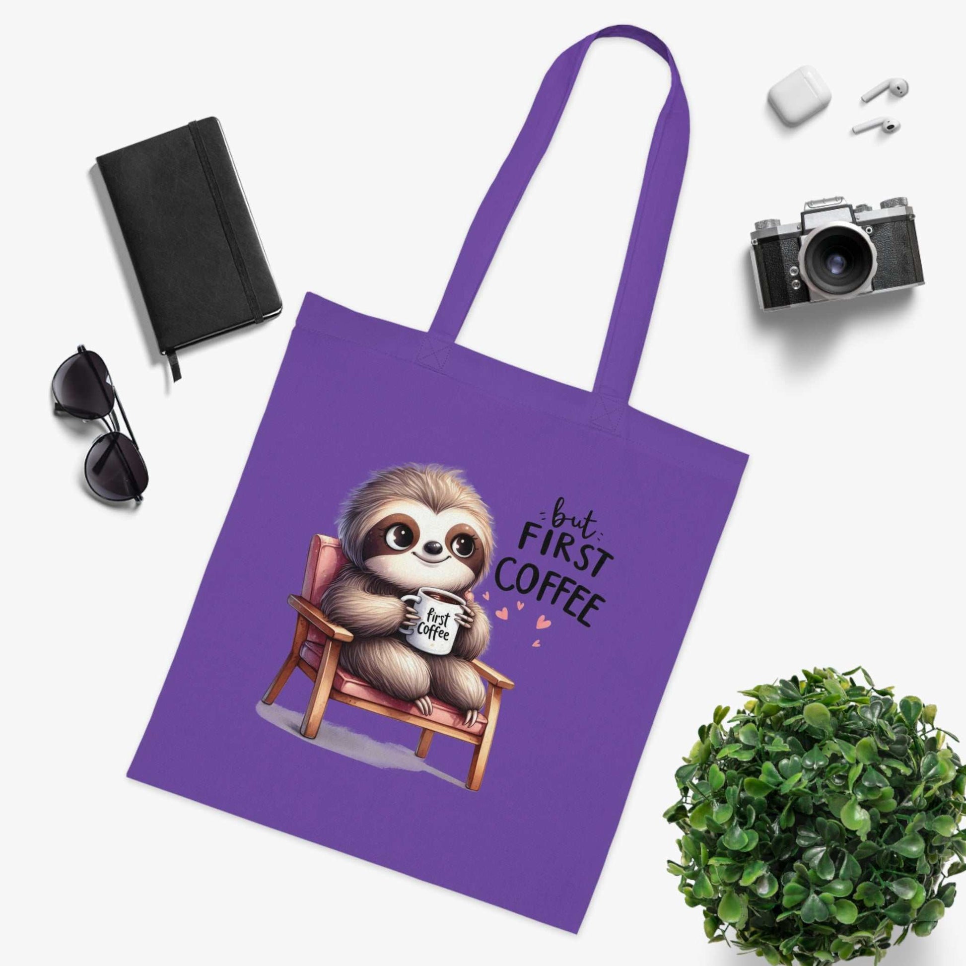 Cute sloth printed cotton tote bag on a purple background with various items nearby.