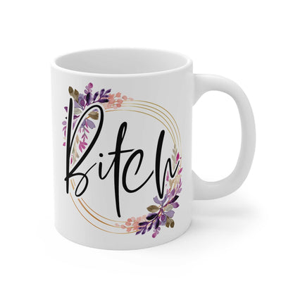 White 11oz ceramic mug with glossy finish featuring the word "Bitch" in stylish script surrounded by purple and pink floral design, microwave and dishwasher safe.