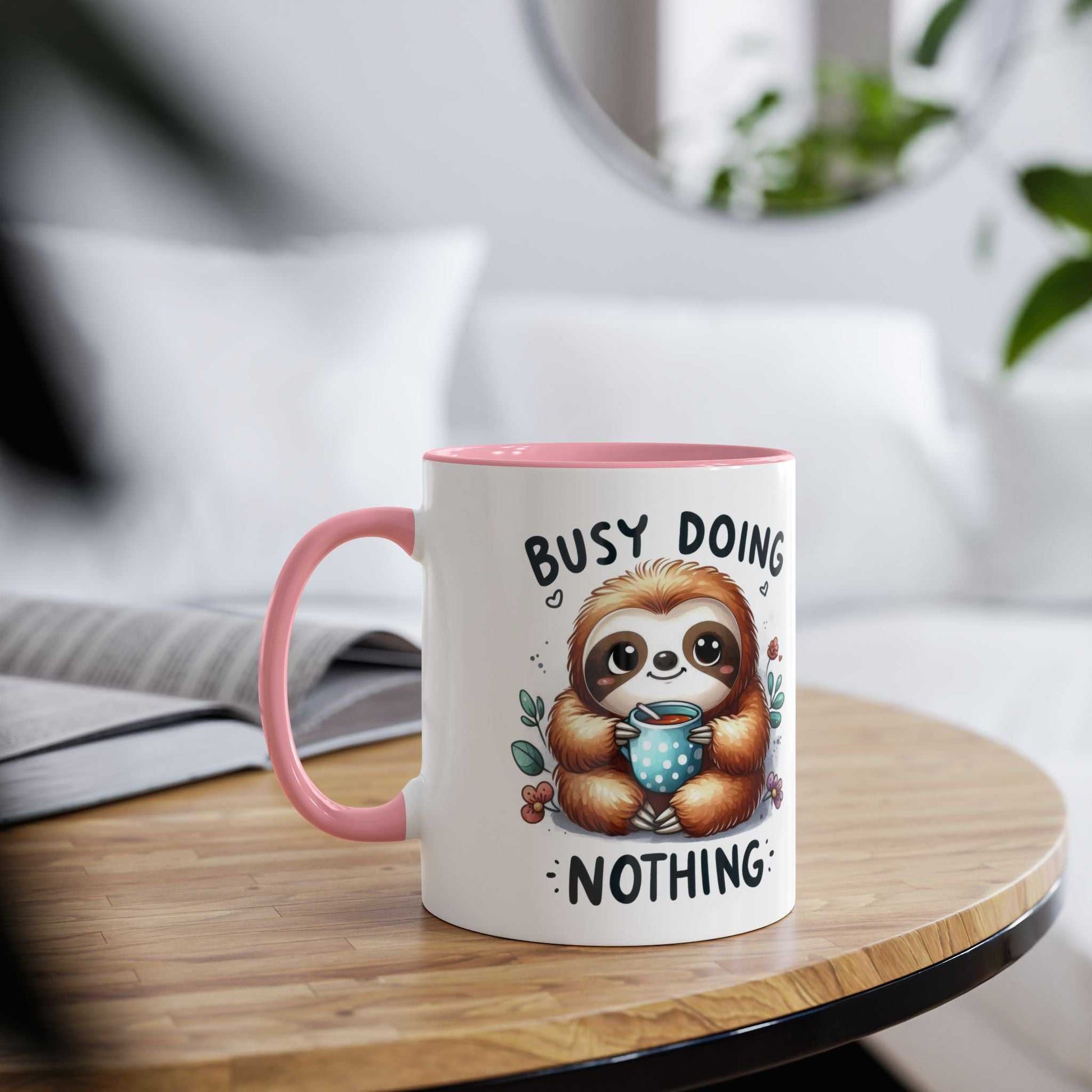 Cute sloth coffee mug with cheerful design and pink handle on table.