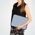 Woman holding misty blue neoprene laptop sleeve with black trim and dual zipper closure