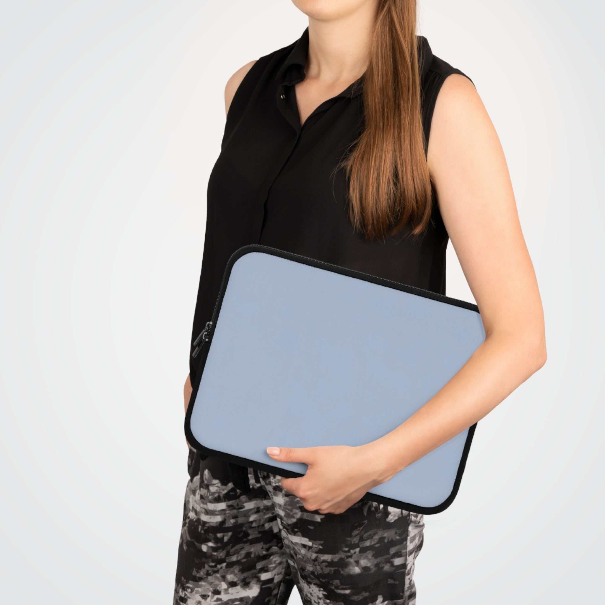 Woman holding misty blue neoprene laptop sleeve with black trim and dual zipper closure