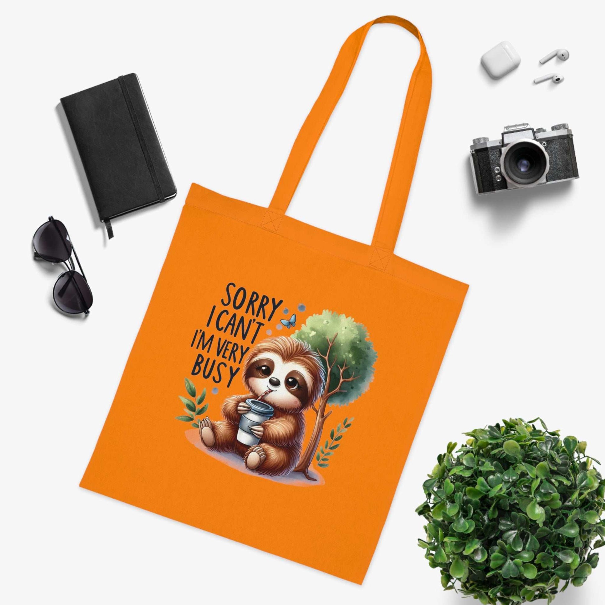 Cute sloth tote bag with vibrant orange color and whimsical design, made from 100% cotton.