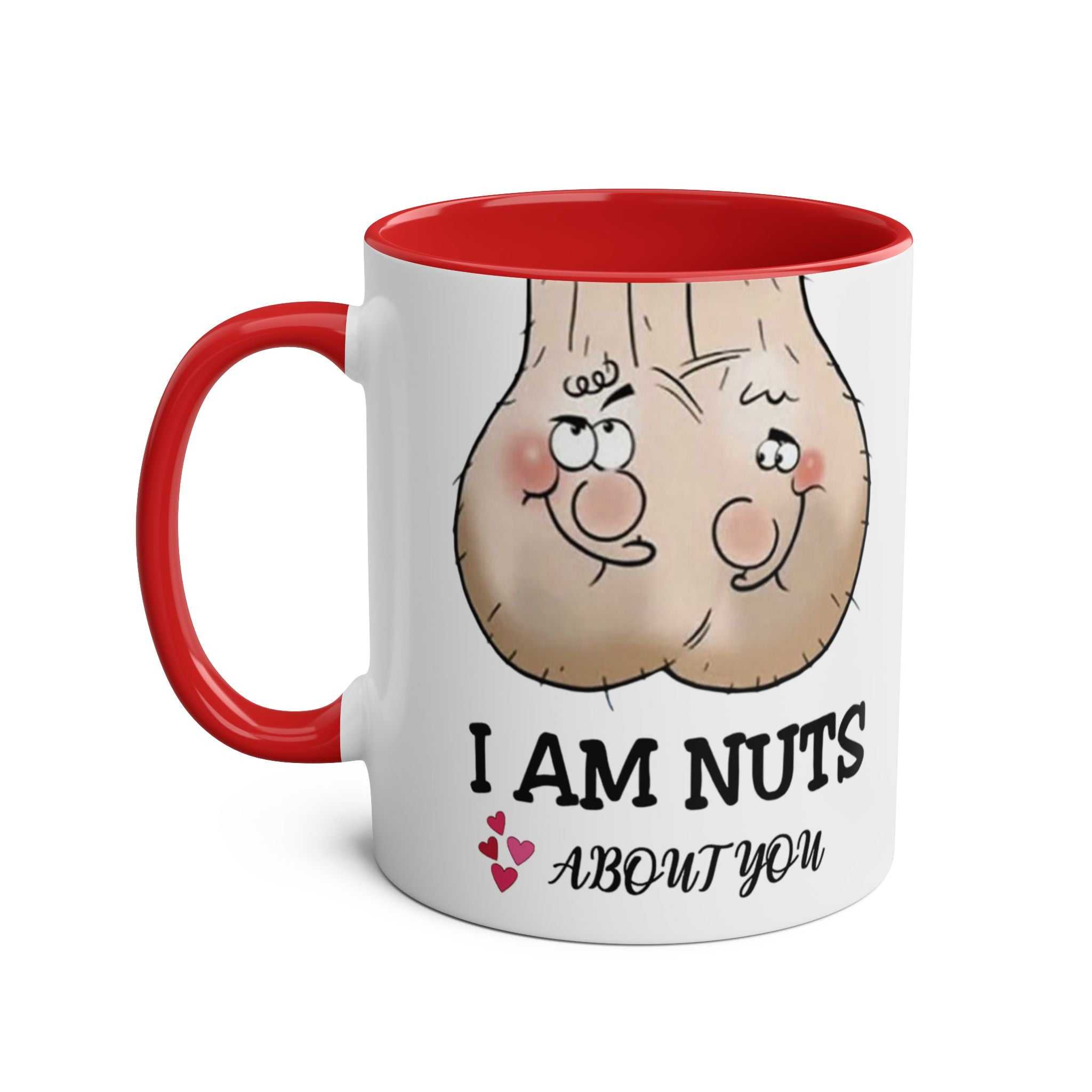 White ceramic "Nuts About You" mug with red handle and interior, featuring cheeky cartoon nuts and playful text.