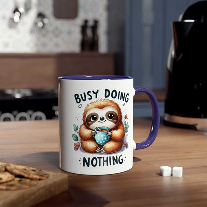 Cute sloth coffee mug with "Busy Doing Nothing" design on a wooden table in a cozy kitchen.