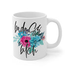 White ceramic mug with "badass bitch" text and colorful floral design, 11oz, glossy finish, microwave and dishwasher safe.