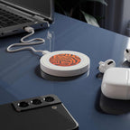 Compact orange tiger print wireless charging pad on desk with smartphone and earbuds
