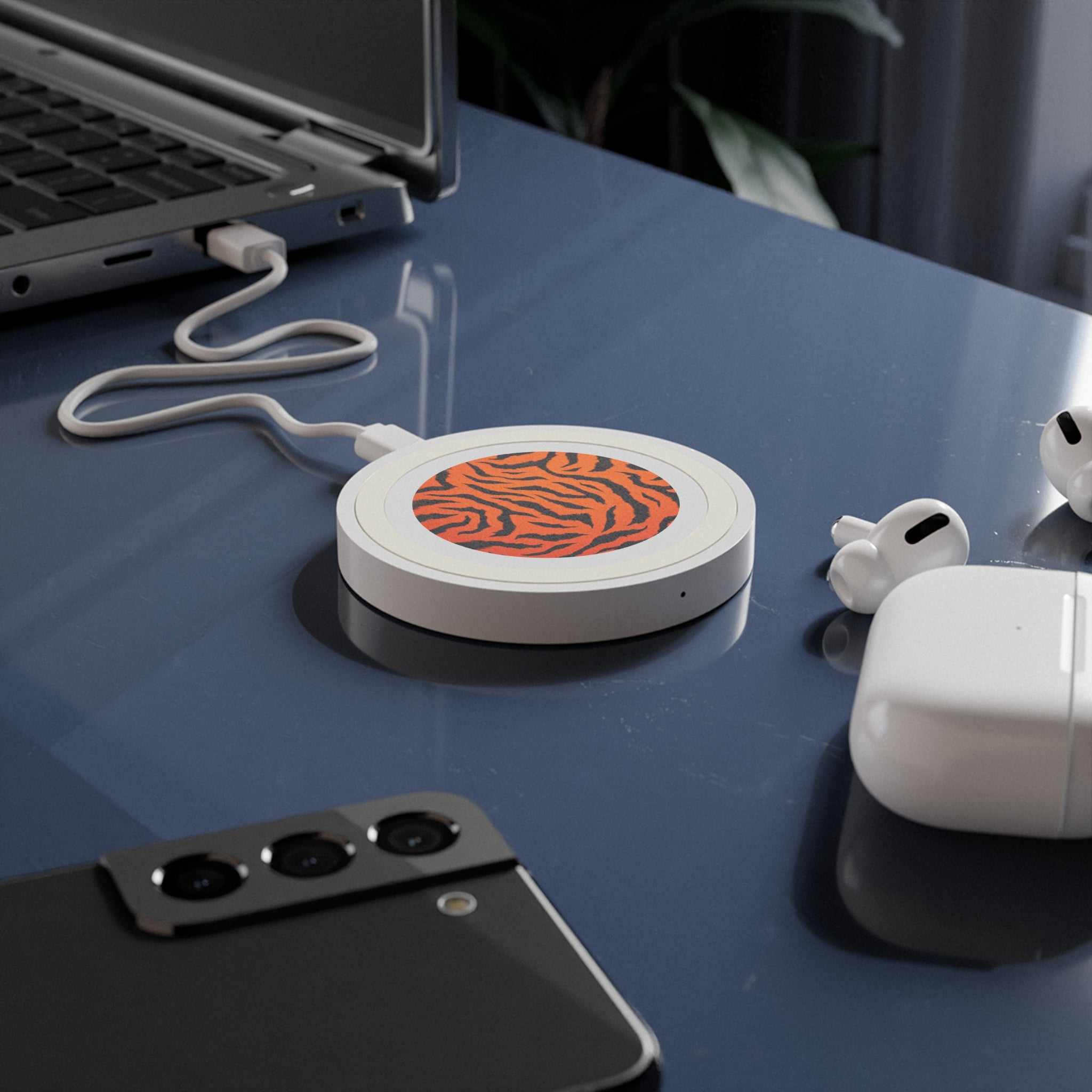 Compact orange tiger print wireless charging pad on desk with smartphone and earbuds