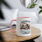 Cute sloth coffee mug with a pink handle and "Natural Born Chiller" printed on it, resting on a table.