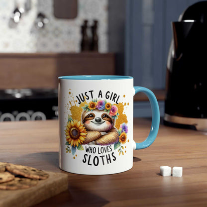 Cute sloth coffee mug with floral design and blue handle, on a kitchen counter.