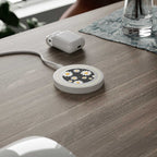 Black Daisy Design wireless charging pad with daisy pattern on a wooden desk with white charging cable and earbud case