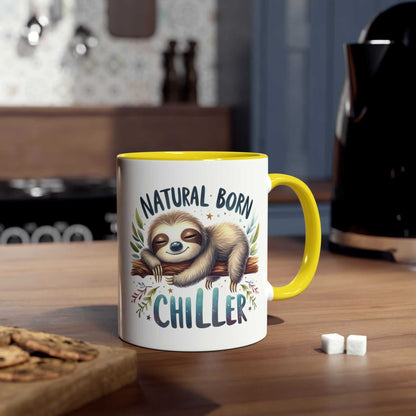Cute sloth coffee mug with "Natural Born Chiller" design on a kitchen countertop.