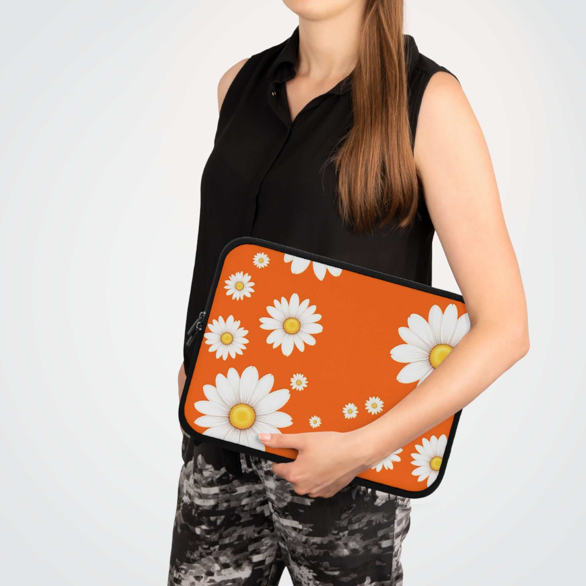 Woman holding orange daisy laptop sleeve with white flowers, made of neoprene with dual zipper and soft foam lining for protection.
