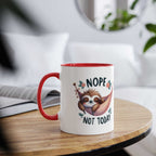 Cute sloth coffee mug with "Nope Not Today" design on table, red handle.