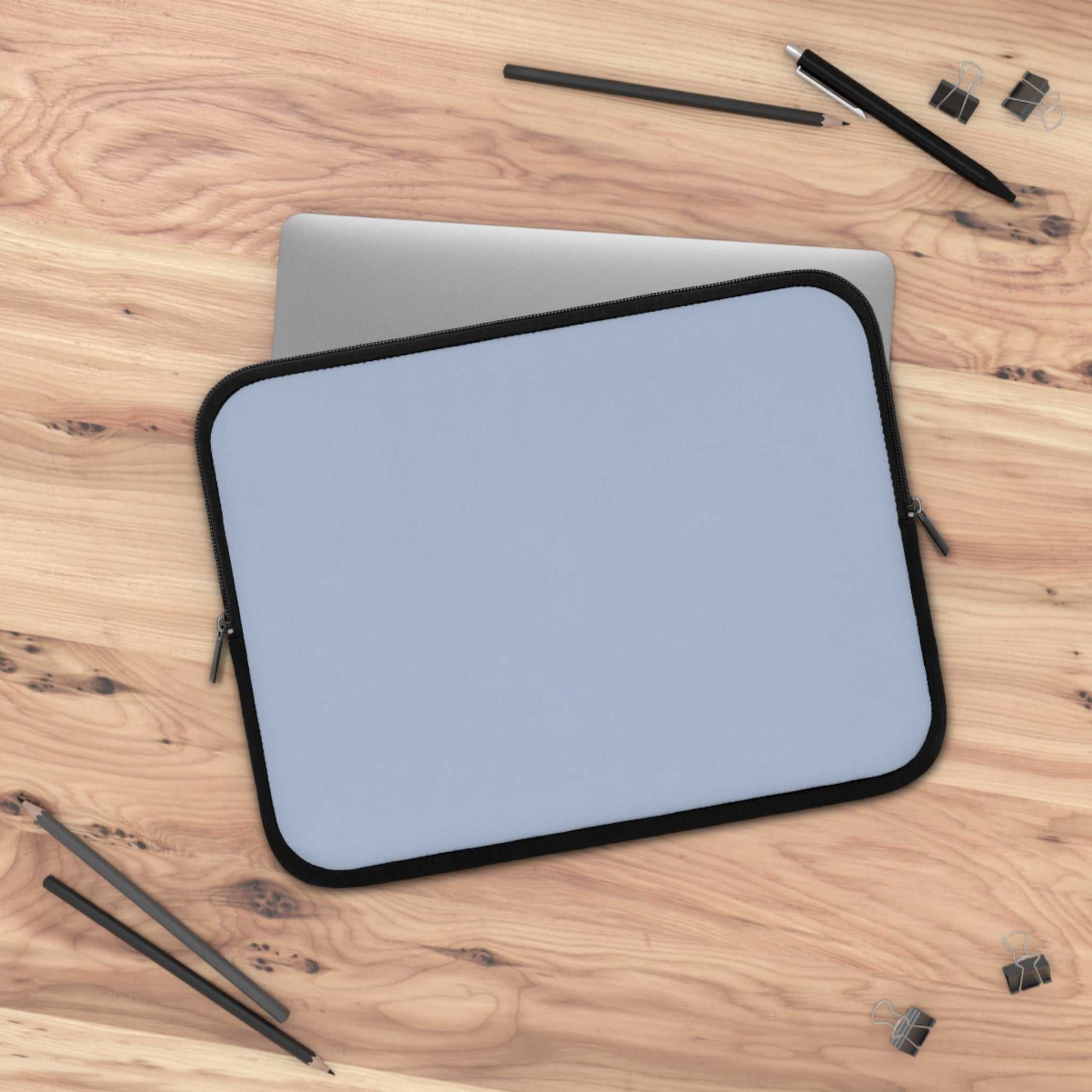 Misty Blue Laptop Sleeve made of durable neoprene with soft foam lining and dual zipper on wooden desk with pencils and clips