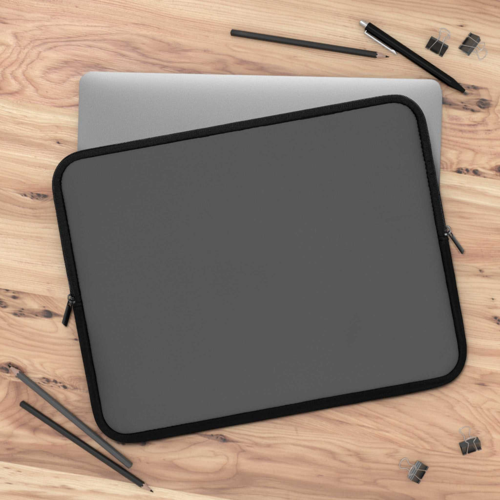 Gunmetal grey neoprene laptop sleeve with soft foam lining and dual zipper on wooden desk