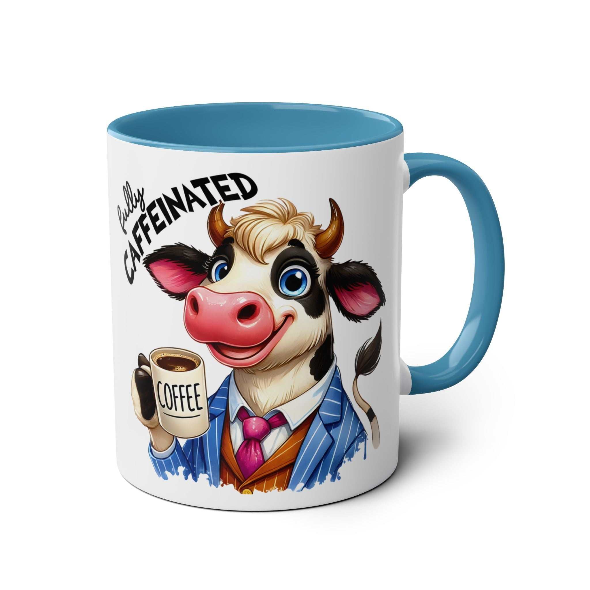 Humorous coffee mug with cow illustration and "Fully Caffeinated" text, featuring a blue handle and interior.