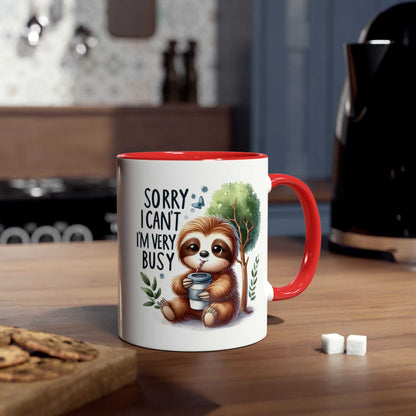 Cute sloth coffee mug with red handle and whimsical design on a kitchen countertop.