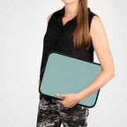 woman holding teal green neoprene laptop sleeve with black trim and zipper protection case