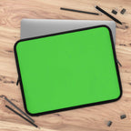 lime green neoprene laptop sleeve with black edges, dual zipper, and soft foam lining on wooden desk