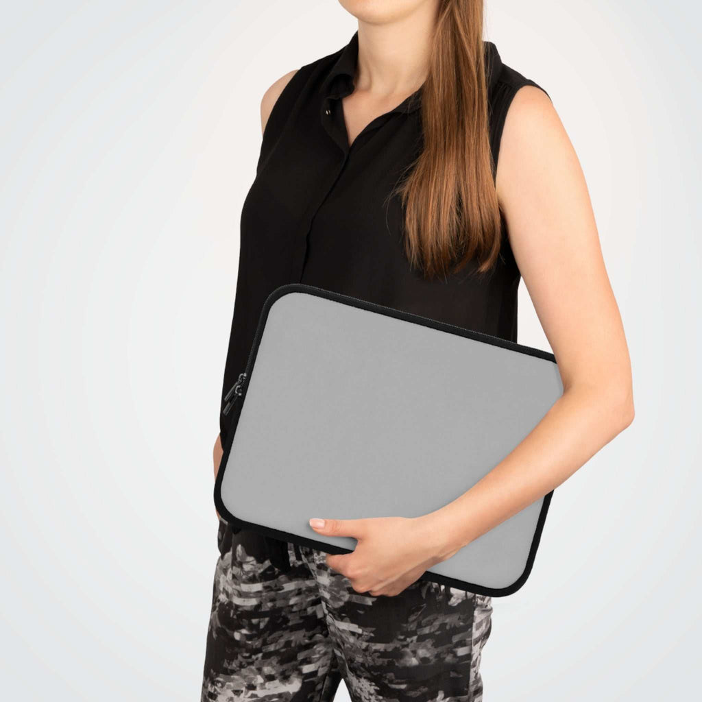 Woman holding silver neoprene laptop sleeve with black trim and zipper