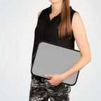 Woman holding silver neoprene laptop sleeve with black trim and zipper