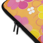 Close-up of retro floral laptop sleeve with bright pink, white, and yellow flowers on orange background and black dual zipper closure