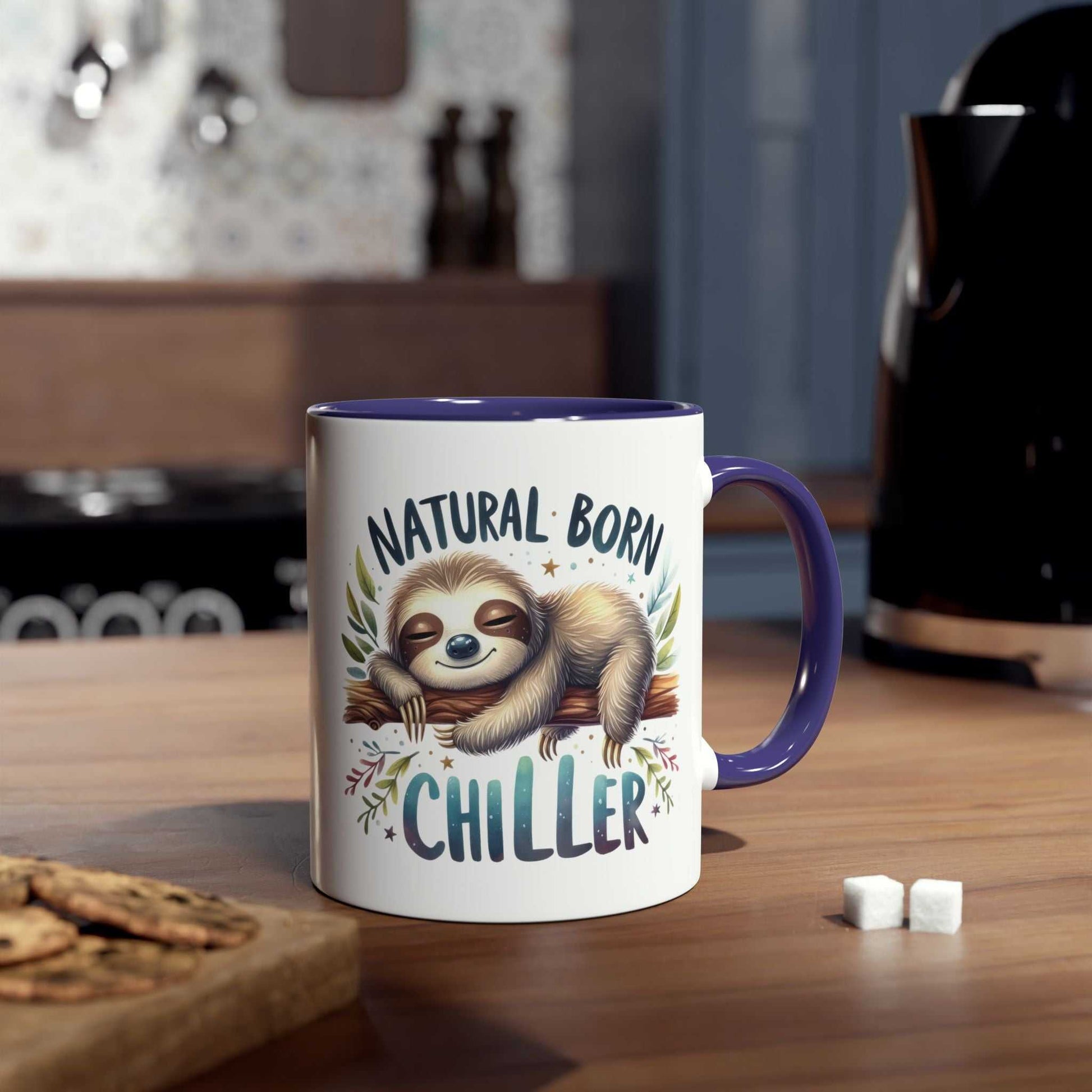 Cute sloth coffee mug with "Natural Born Chiller" design on a kitchen counter.