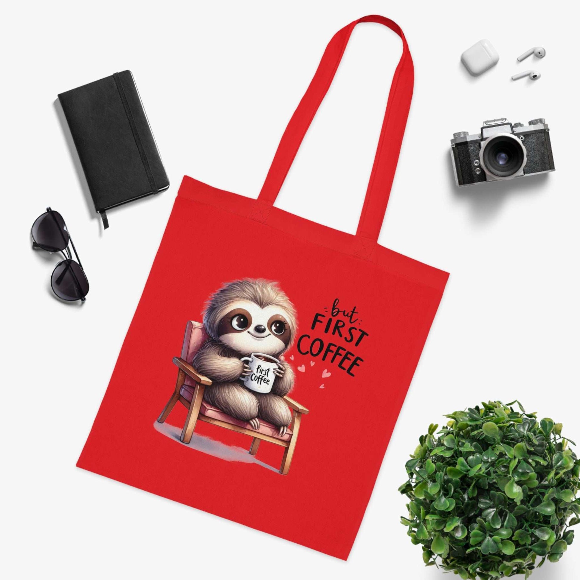 Cute sloth design cotton tote bag surrounded by accessories, vibrant red, perfect for sloth lovers and everyday use.