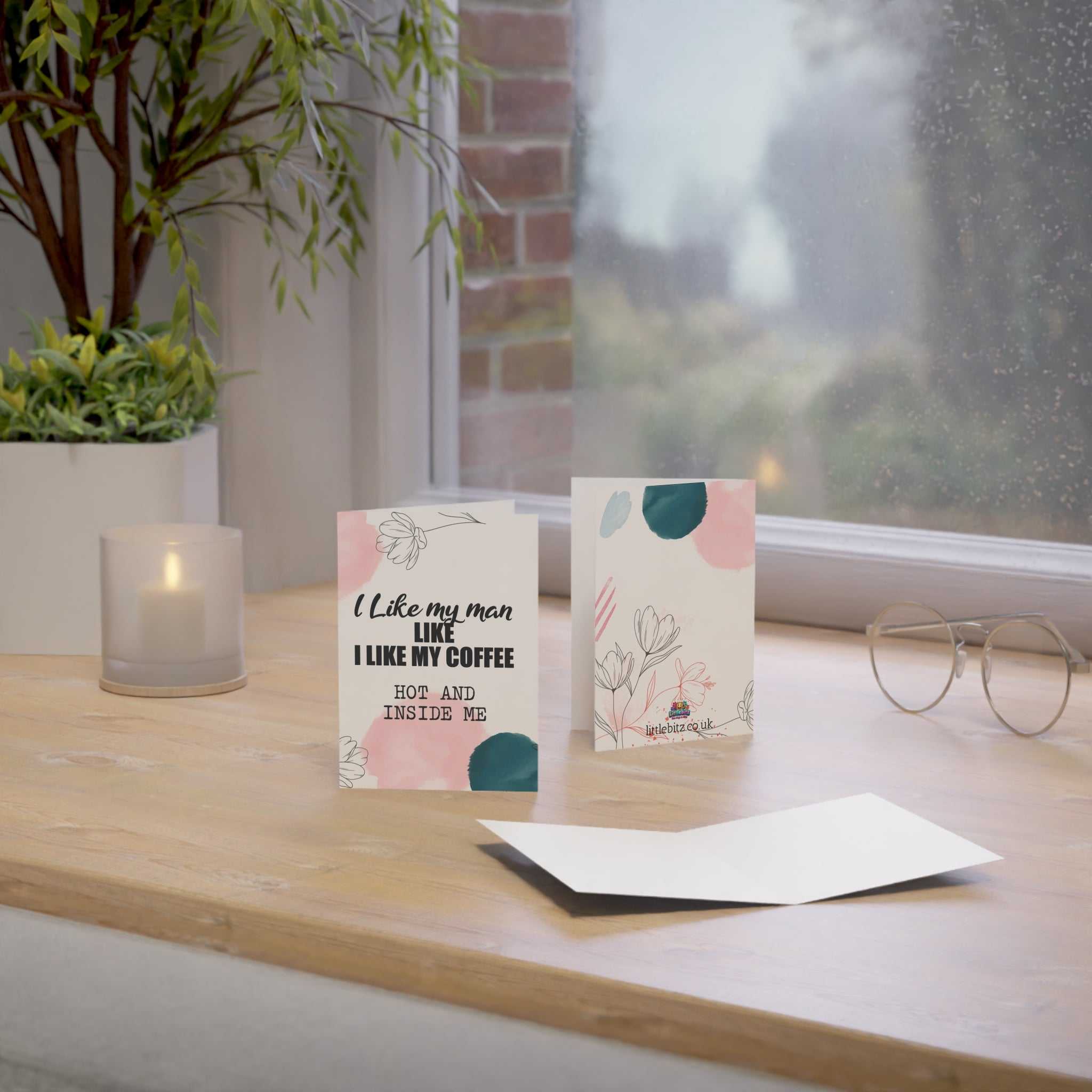 Cheeky Fun Greeting Card on wooden table near window with plants.