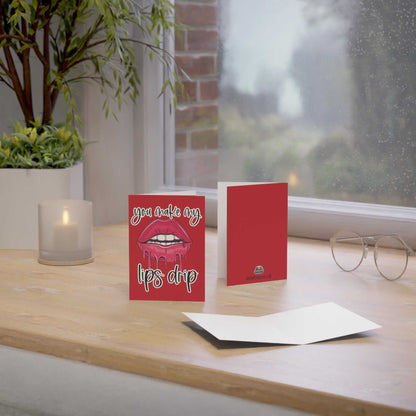 Cheeky 'You Make My Lips Drip' greeting card on a wooden table with envelope, perfect for special occasions.