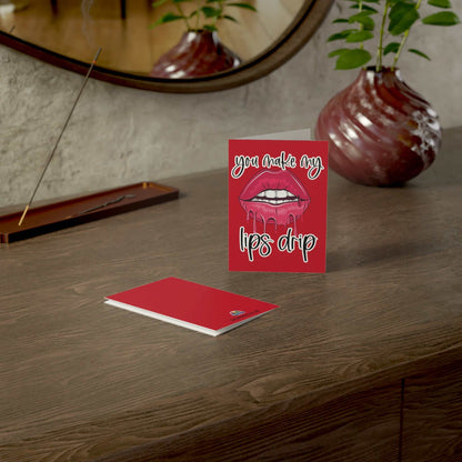Cheeky "You Make My Lips Drip" Valentine's Day Greeting Card on a wooden table with envelope.