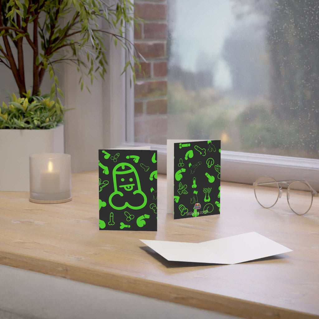 Cheeky green willy greeting card on a table with envelope and humorous design.