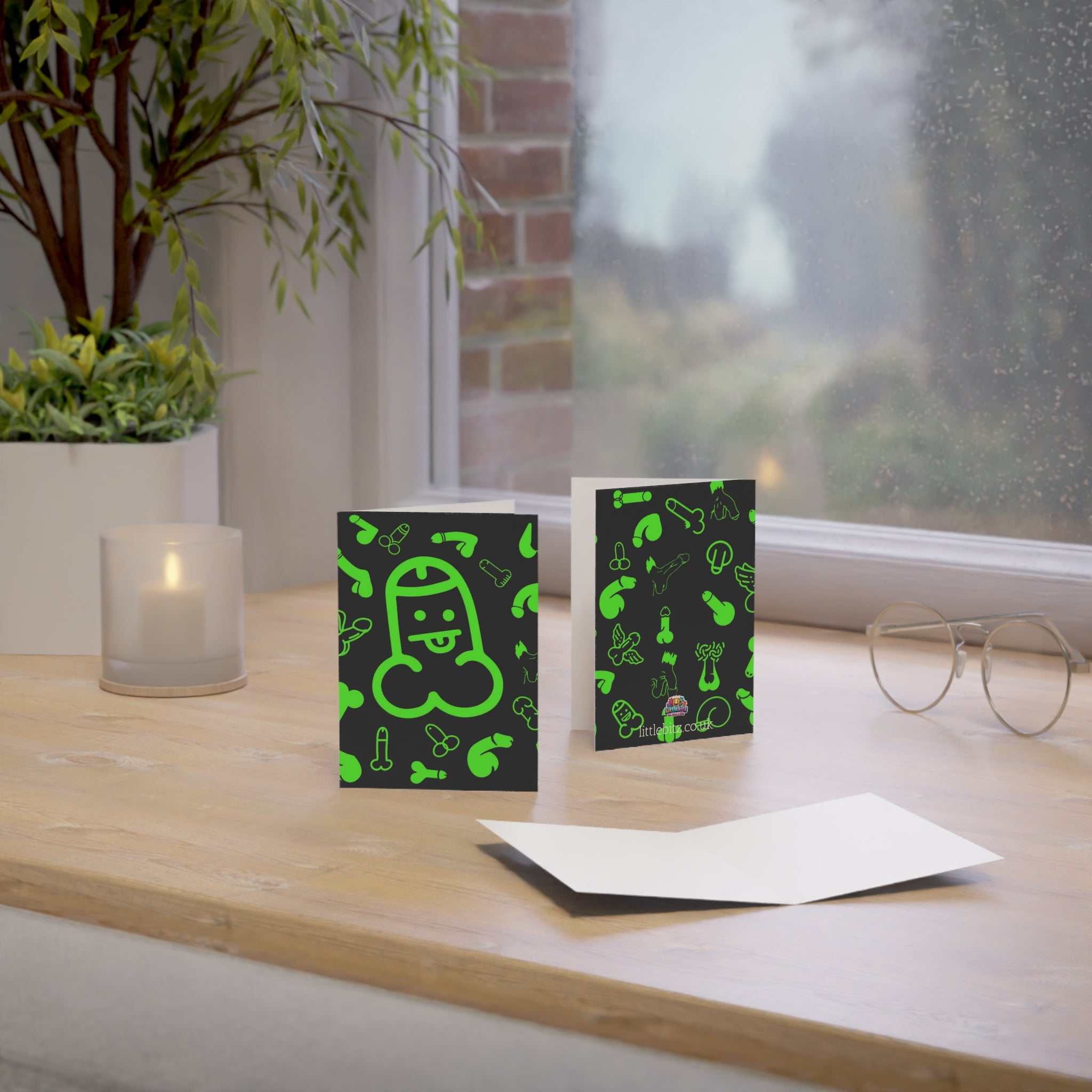 Cheeky green willy greeting card on a table with envelope and humorous design.